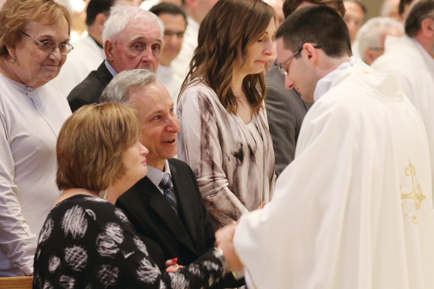 Father Dufour, in an emotional moment for the family, offers a blessing upon his parents, Jerry and Denise Dufour, as his sister Elise Augustine holds back tears of joy.